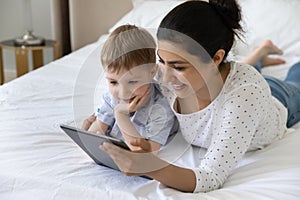 Happy stepmom and little son reading book on tablet together