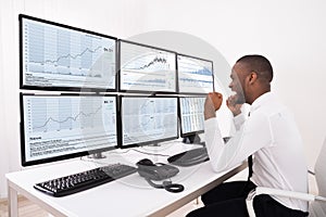 Happy Stock Market Broker Looking At Graphs On Multiple Computer