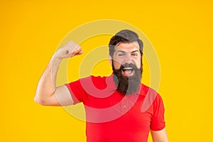 happy strong guy with beard and hairstyle on yellow background, strength