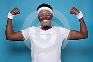 Happy strong man in sport gym, shows muscles, glad to be fit and healthy.