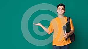 Happy student with books holding something on palm