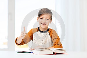 Happy student boy with textbook showing thumbs up