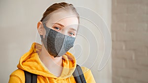 Happy student on brick wall. Young beautiful woman smiles sincerely, wearing protective mask portrait with backpack. Teen Girl