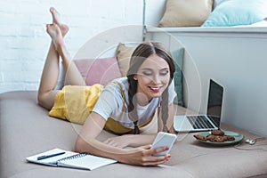 happy student with earphones and laptop writing