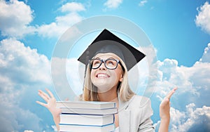 Happy student girl in bachelor cap with books