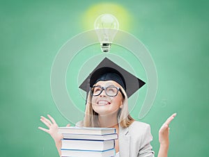 Happy student girl in bachelor cap with books