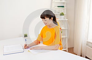 Happy student girl with book and notebook at home