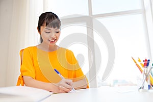 Happy student girl with book and notebook at home