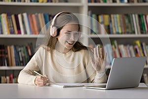 Happy student girl in headphones enjoying studying in library