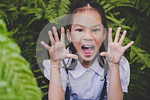 Happy student girl making a scared face in a green garden, for children hapiness and fun concept