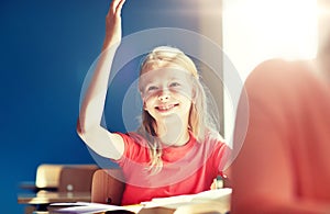 Happy student girl raising hand at school lesson