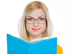 Happy student girl reading book in glasses