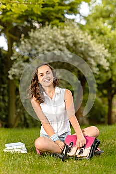 Happy student girl sitting grass open schoolbag