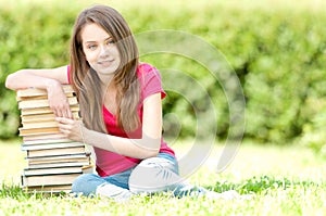 Happy student girl sitting on pile of books