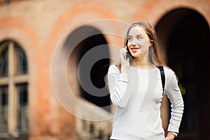 Happy student girl speaking mobile outdoors near University