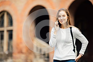 Happy student girl speaking mobile outdoors near University