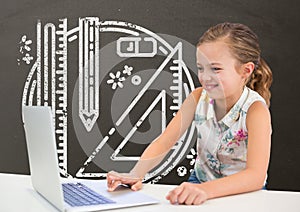 Happy student girl at table using a computer against grey blackboard with school and education graph