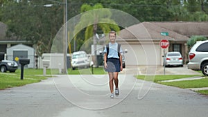 Happy student girl walking on rural street returning home from school