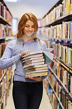 Happy student girl or woman with books in library