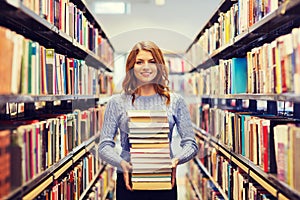 Happy student girl or woman with books in library