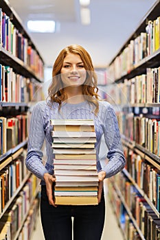 Happy student girl or woman with books in library