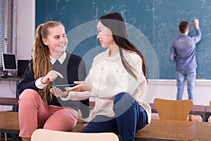 Happy student girls with phone in schoolroom