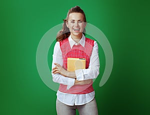 Happy student holding yellow book isolated on green background