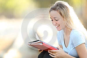 Happy student learning reading notes outdoors