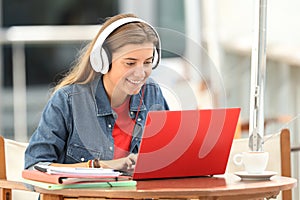 Happy student listening a video tutorial on line photo