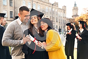 Happy student with parents after graduation ceremony