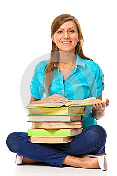 Happy student sitting on a floor with a stack of books