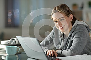 Happy student using laptop looking at you
