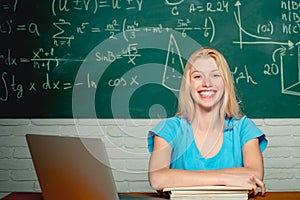 Happy student. Woman working on laptop computer over chalkboard background. College Student. Student sitting at table