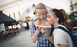 Happy students eating pizza on street