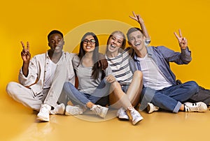 Happy students having fun over yellow studio background