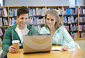 Happy students with laptop in library