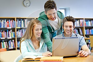 Happy students with laptop in library