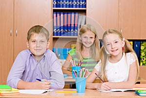 Happy students sitting at their desks in the classroom