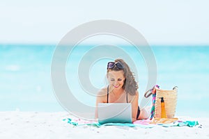 Happy stylish 40 year old woman on white beach using internet