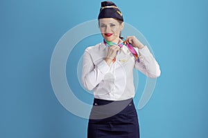 happy stylish air hostess woman on blue adjusting scarf