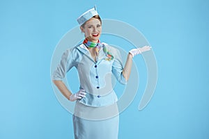 happy stylish air hostess woman on blue presenting something