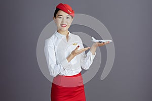 happy stylish asian female air hostess isolated on gray