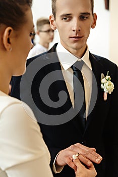 Happy stylish bride and elegant groom exchanging wedding rings at ceremony at church