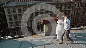 Happy stylish couple bride and groom walking on the roof.