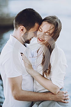 Happy stylish couple in love hugging on the beach in summer cit