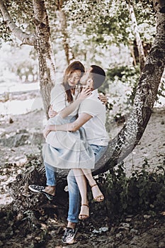 Happy stylish couple in love hugging and kissing in summer park