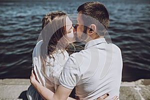 Happy stylish couple in love kissing on the beach in summer city