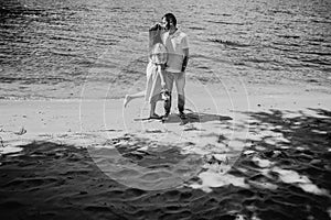 Happy stylish couple in love kissing on the beach in summer city