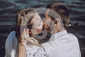 Happy stylish couple in love kissing on the beach in summer city