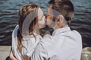 Happy stylish couple in love kissing on the beach in summer city